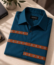 Aachari navy teal cotton shirt featuring brown leather straps with metallic eyelet details on a folded display.